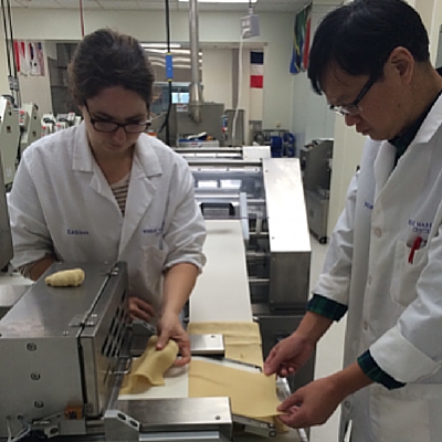 Cutting cracker dough sheets to line up for lamination.